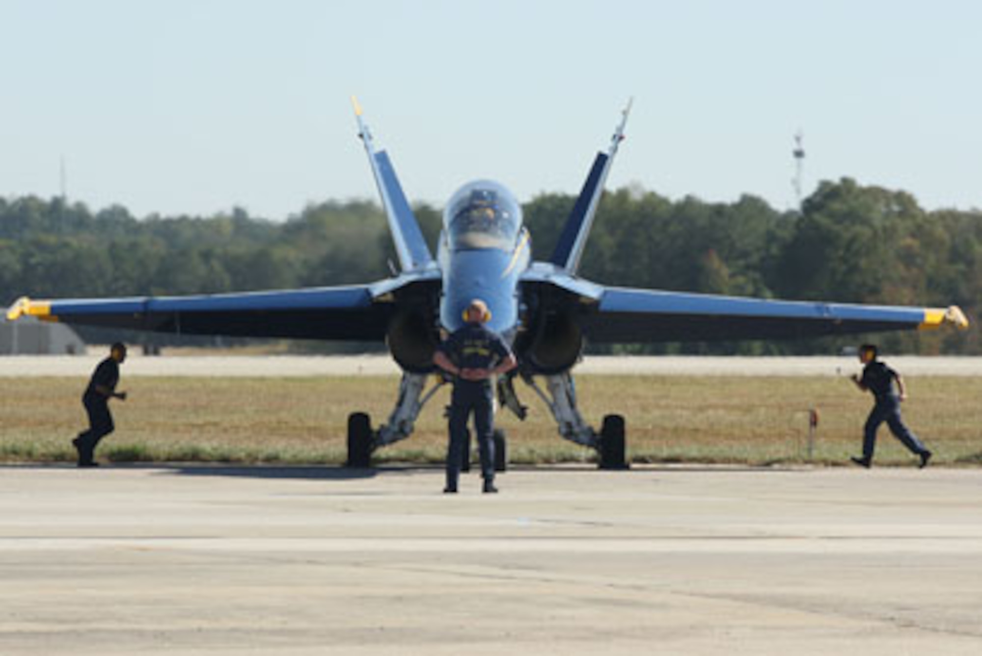 Blue Angel air crew technicians hurry to remove the wheel chocks during the ceremonial opening practice performance before take-off Oct. 15. (U.S. Air Force Photo/Don Peek)