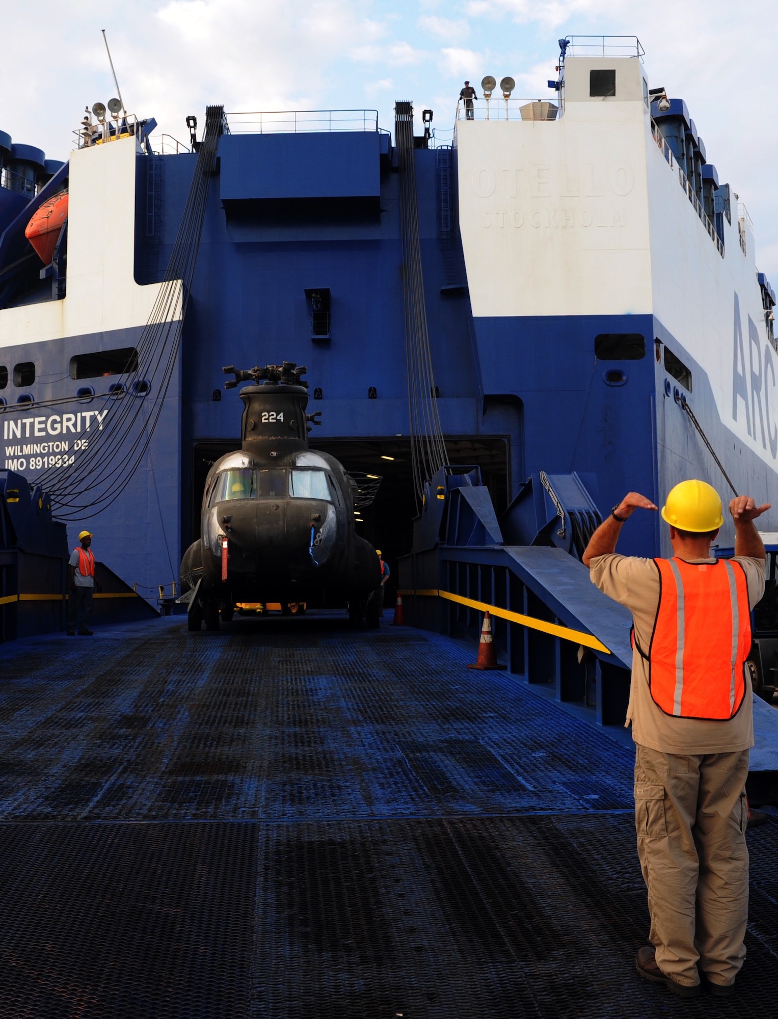 A civilian contractor signals for spotters to move the CH-47 forward down the off-ramp at the TC dock Oct. 14, 2010, on Joint Base Charleston Weapons Station, S.C. The TC dock is open to cargo vessels dock around the clock but only off-loads and on-loads cargo during a 12-hour window.  (U.S. Air Force photo/Senior Airman Timothy Taylor) 