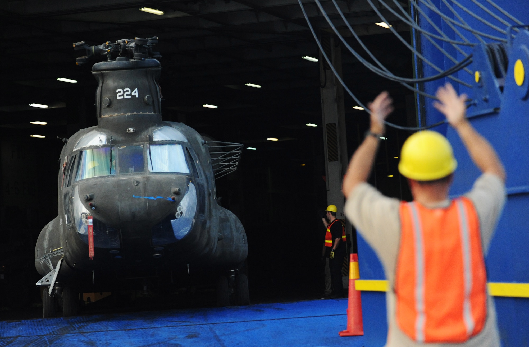 A civilian contractor signals for spotters to move the CH-47 forward down the off-ramp at the TC dock Oct. 14, 2010, on Joint Base Charleston-Weapons Station, S.C. Different cargo vessels have smaller or larger storage capacities and require different lengths of time for off-loading. Some of the larger vessels arrive at the docks with more than 1,900 pieces of equipment and can take more than two weeks to off-load. (U.S. Air Force photo/Senior Airman Timothy Taylor) 