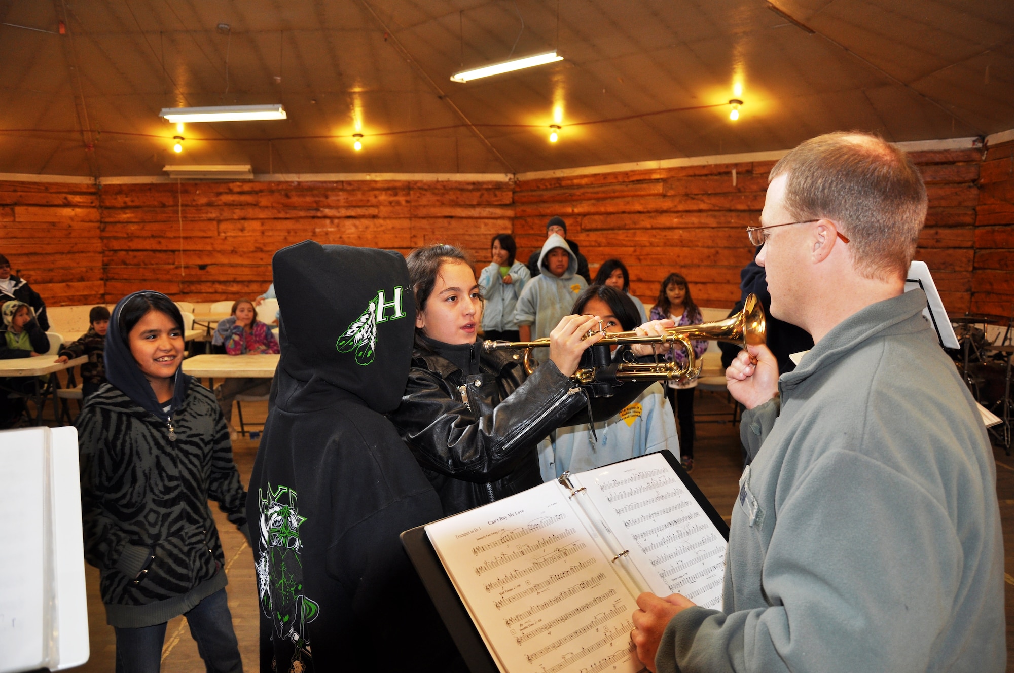 Air Force Staff Sgt. Mark Nixon, newest member of Alaska Brass, talks with a youngster in Huslia and shows her how to play a few notes on the trumpet. (U.S. Air Force photo/TSgt John Rider)