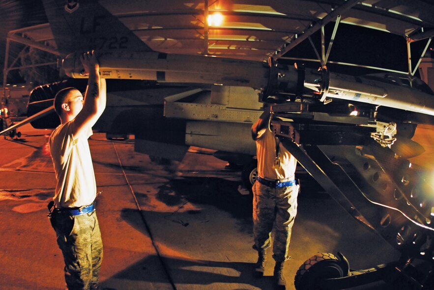 Senior Airman Samuel Perez, 309th Aircraft Maintenance Unit weapons crew member, and Staff Sgt. Donald Sheppard, 309th Aircraft Maintenance Unit crew chief, load a missile onto an F-16 Fighting Falcon in preparation for the next day's flight. The maintainers will also wash and repair the jets. (U.S. Air Force photo/Senior Airman C.J. Hatch)