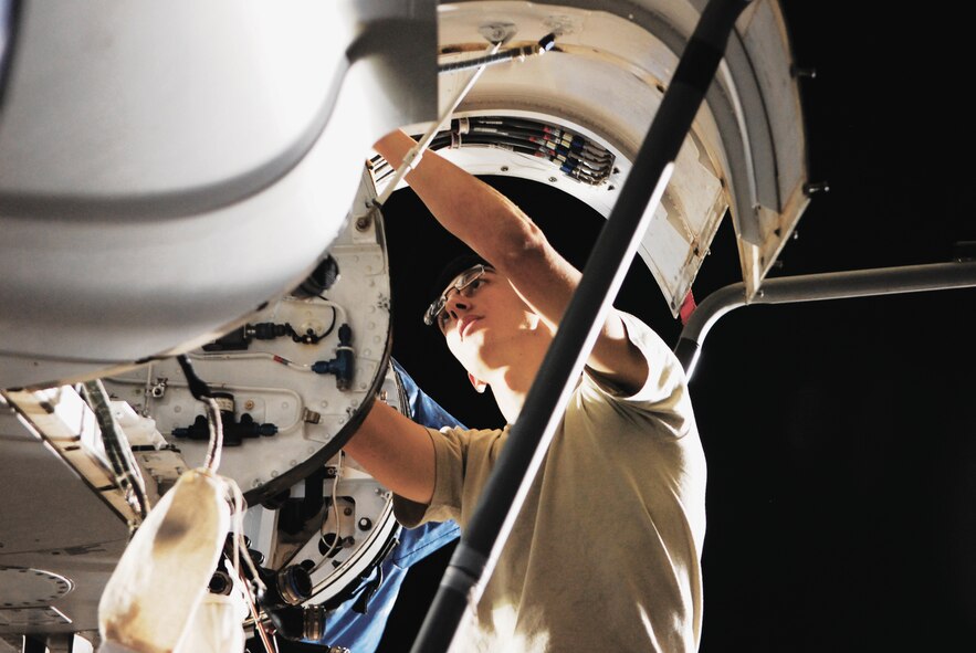 Airman 1st Class David Shinn, 309th Aircraft Maintenance Unit crew chief, reaches inside an F-16 Fighting Falcon to reroute a harness.  "Working nights is a good job; it's quiet so you get to focus on what you're doing.  During the day I would just do a launch and recovery."  (U.S. Air Force photo/Senior Airman C.J. Hatch)