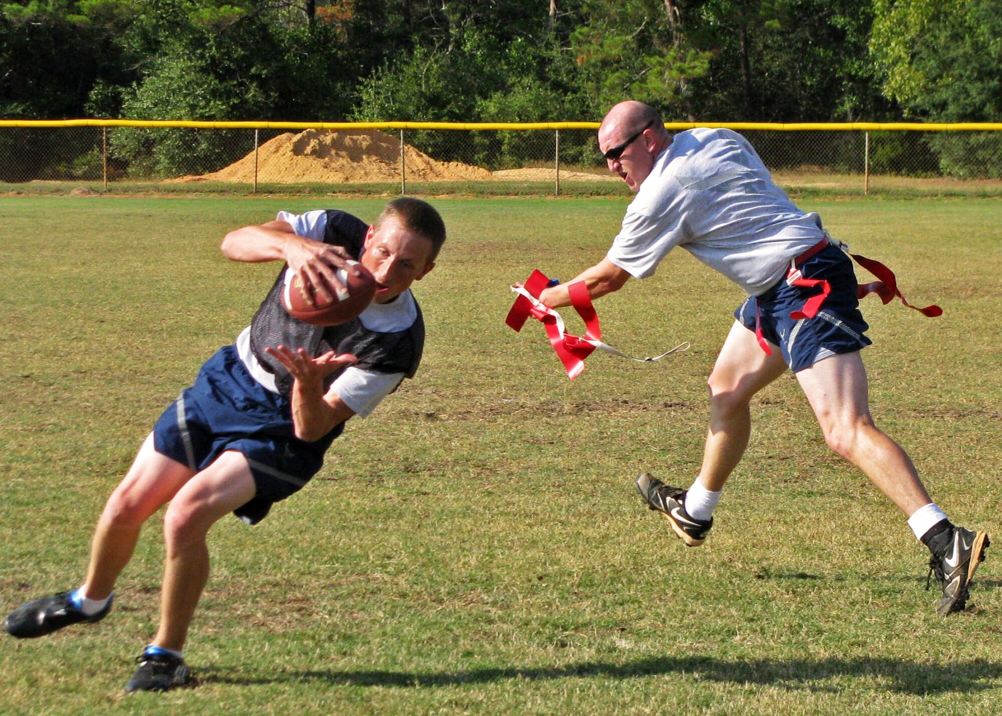 Capt. Daniel Fredberg, 96th Air Base Wing, comes down with the ball as Capt. Nick Coleman, 46th Test Wing pulls the flag during the 46th and 96th’s flag football game, Oct. 14 at Eglin Air Force Base, Fla.  The 46 team defeated the 96, 21-14.  (U.S. Air Force photo/Irene Freiberg)