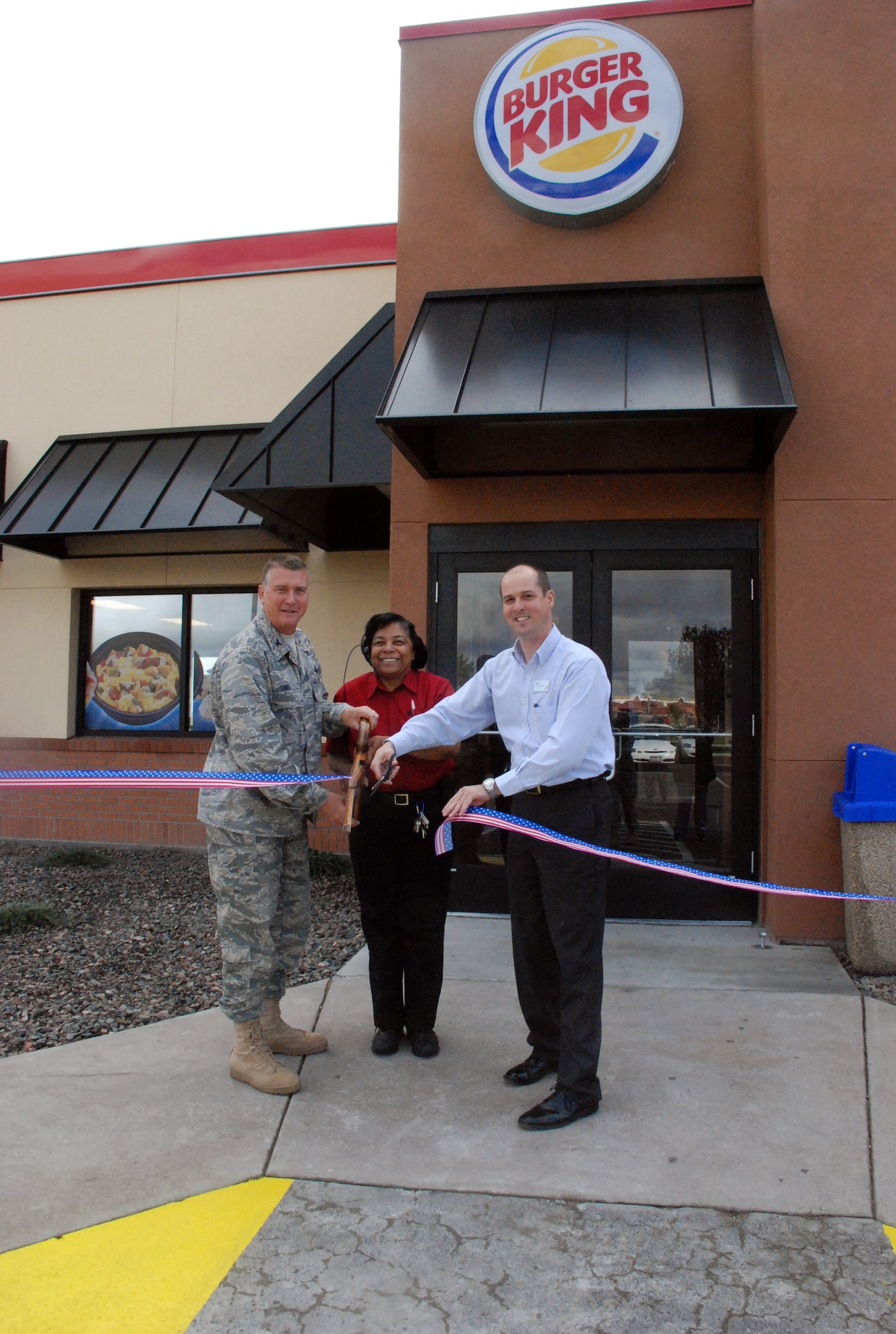 Colonel Greg Tims, 90th Missile Wing commander, Desiree Taylor, Burger King manager and Jeff Hyatt, AAFES Regional Manager, cut the ribbon for F. E. Warren’s reopening of Burger King here on Tuesday.  The base eatery was closed for about 90 days due to renovations, several of which included a new spacious dining room and more efficient kitchen space. (U.S. Air Force photo by 1st Lt. Brooke Brzozowske)