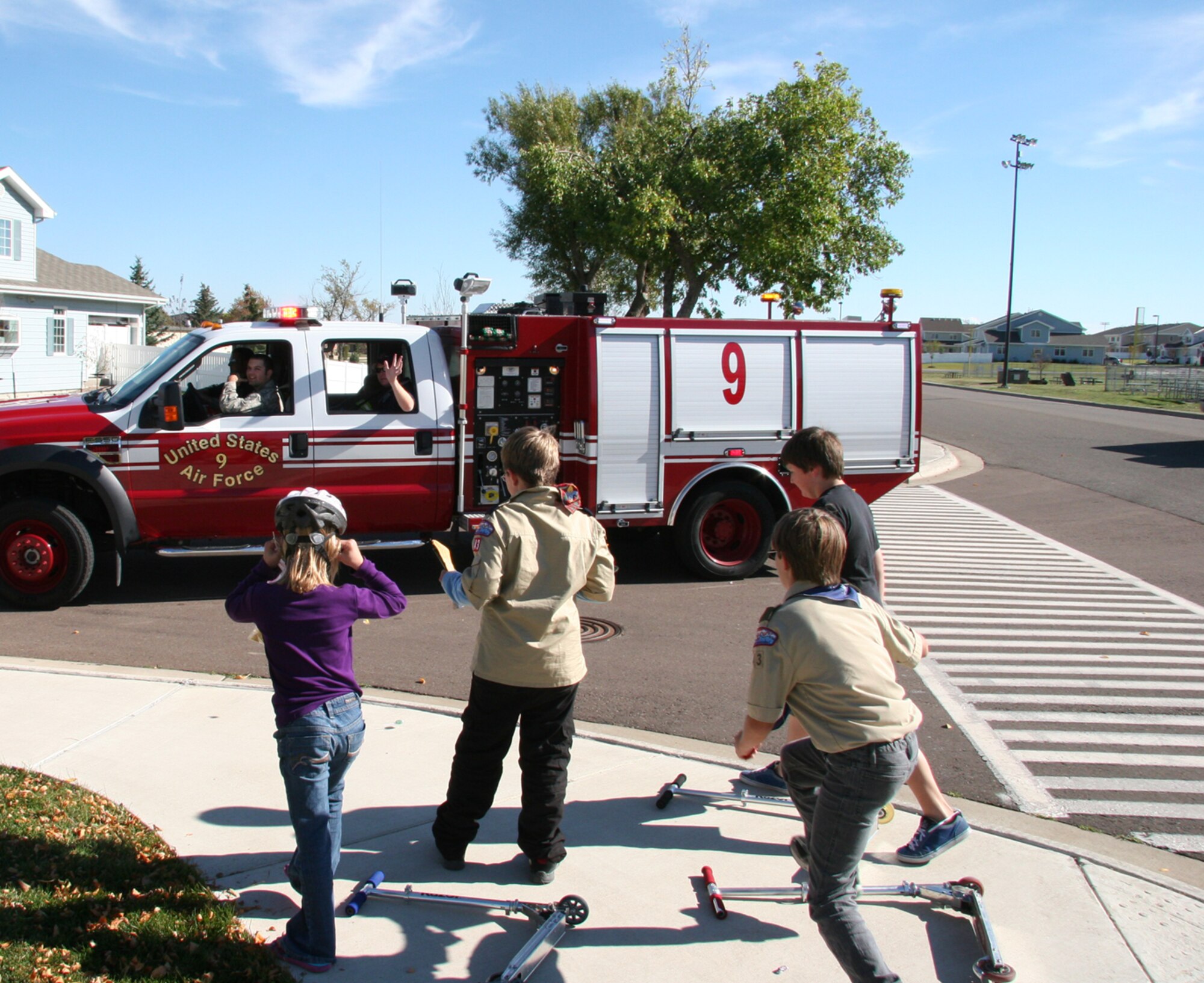 Malmstrom firefighters wave to youth and throw candy as they parade through base housing Oct. 9 as part of National Fire Safety Week. The annual fire truck parade brought firefighters and trucks from Sand Coulee, Great Falls, Black Eagle and the Montana Air National Guard to name a few. (U.S. Air Force photo/Staff Sgt. Dillon White)