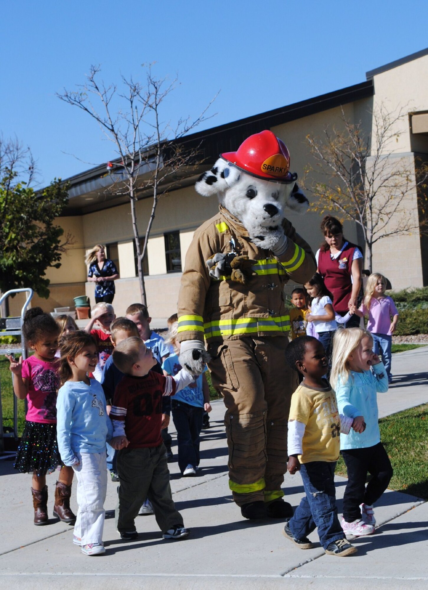 “Sparky,” the fire dog, and a group of children walk from the Child Development Center to the parking lot where a group of Malmstrom firefighters were on hand to tell the children about fire safety and let them sit in the driver’s seat during a fire education display Oct. 6. (U.S. Air Force photo/Airman 1st Class Kristina Overton)