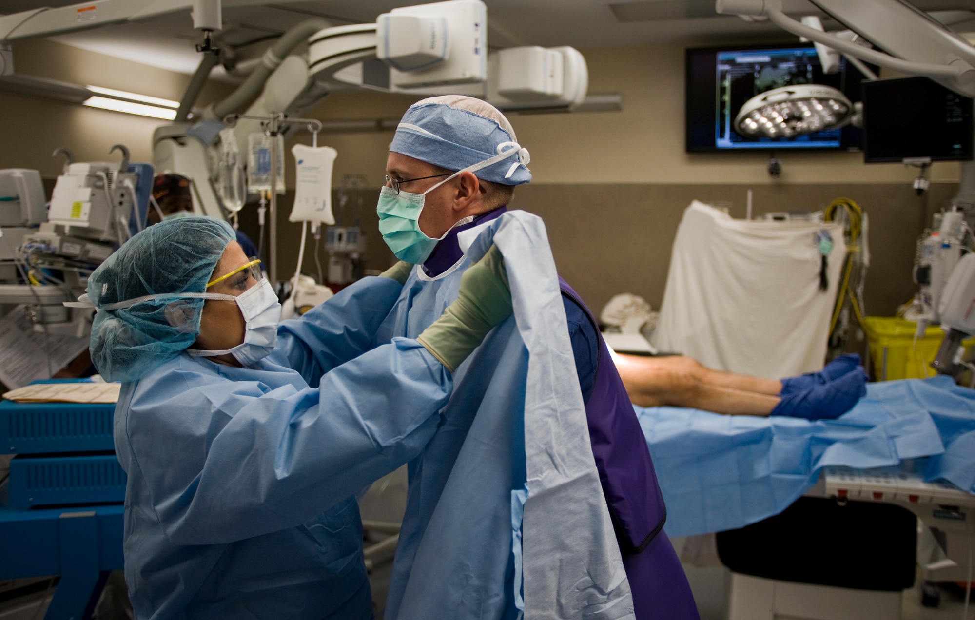 Sara Rodriguez helps Lt. David Morrow with his operating gown before an abdominal aortic aneurysm procedure surgery Oct. 14, 2010, in the cardiovascular operating room at the David Grant USAF Medical Center, Travis Air Force Base, Calif. This is only the third surgery to take place in the new state-of-the-art operating room that integrates advanced robotic technology for complex cardiac and vascular surgical procedures. Ms. Rodriguez is an operating room technician. Lieutenant Morrow is a medical student. (U.S. Air Force photo/Tech. Sgt. Bennie J. Davis III)