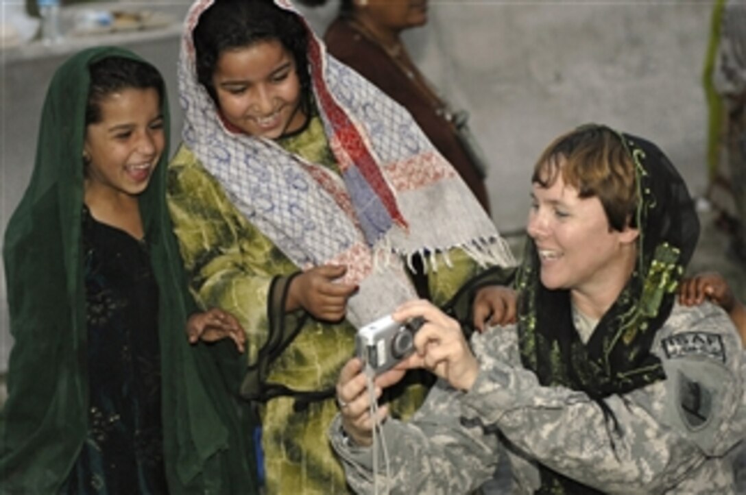 U.S. Army Capt. Marie Orlando shows Afghan girls photos during their weekly Girl Scout meeting at Forward Operating Base Finley-Shields, Afghanistan, on Oct. 9, 2010.  Orlando is the information operations officer with the agriculture development team assigned to the base.  