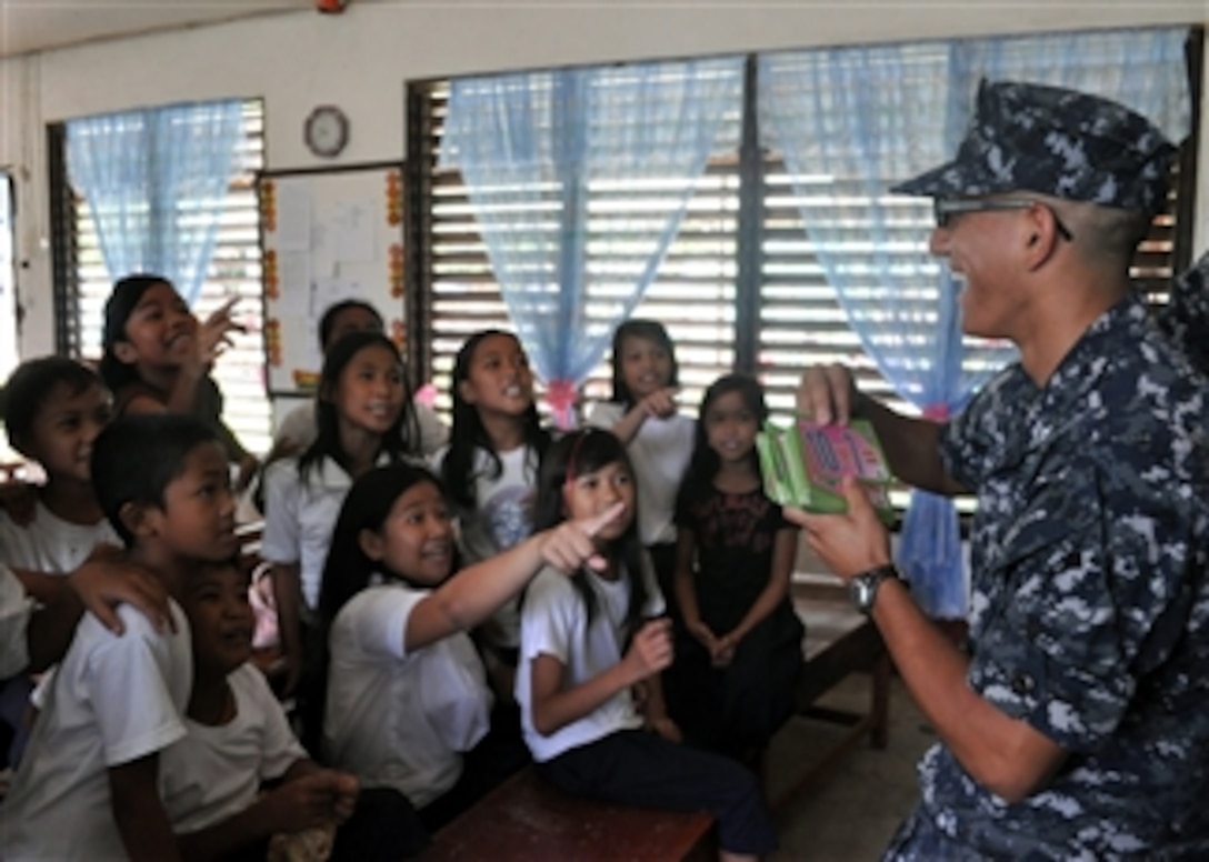 U.S. Navy Petty Officer 3rd Class Johan Olarte plays a mathematics game with children during a community relations event at San Nicolas Elementary School in San Antonio, Philippines, on Oct. 13, 2010.  Olarte is deployed aboard the amphibious transport dock USS Denver (LPD 9), which is underway for a patrol in the western Pacific Ocean.  