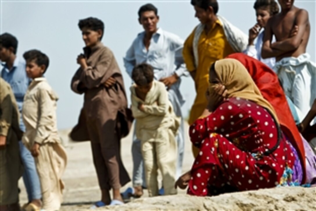 Pakistani flood victims wait patiently as U.S. Marines unload food off of a CH-53E Super Stallion helicopter during flood relief operations in Sindh province, Pakistan, Oct. 15, 2010. The Marines are assigned to the Marine Medium Tilt Rotor Squadron 266, 26th Marine Expeditionary Unit.