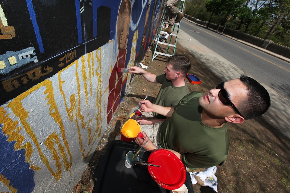 Staff Sgt. Jorge Dimmer, graphics chief, Marine Corps Recruiting Command, uses his artistic skills to help create a mural in Boston’s Hyde Park for Marine Week Boston. Dimmer is slated to be the officer in charge of combat camera for the 3rd Marine Air Wing in Miramar, Calif. upon completion of The Basic School.