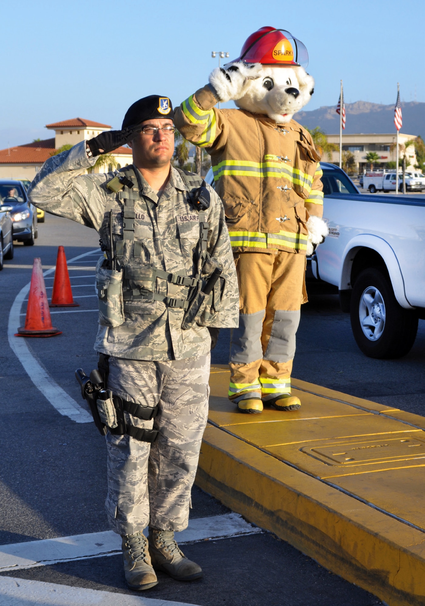 Senior Airman Pablo Castillo, 452nd Security Forces Squadron, and Sparky (played by Staff Sgt. Jarod Bernard, March Fire Department) observe morning colors at the main gate Oct. 7 with a salute. Sparky and fire department staff were at the gate to hand out flyers to drivers during the morning rush. (U.S. Air Force photo by Master Sgt. Linda Welz)
