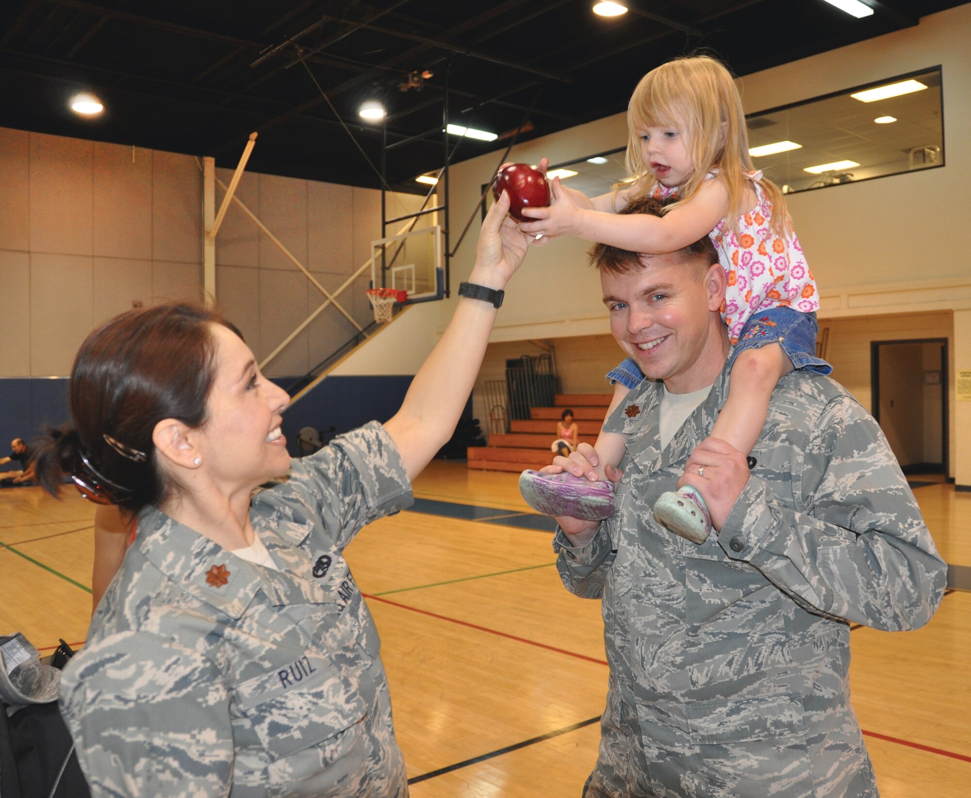 Maj. Anna Ruiz, 452nd Mission Support Group executive officer, hands an apple to Paige, two-year-old daughter of Maj. Zack Jensen, 452nd Logistics Readiness Squadron commander, during the March Fitness Fair Oct. 2. The fair provided information on healthy lifestyles.  (U.S. Air Force photo by Master Sgt. Linda Welz)