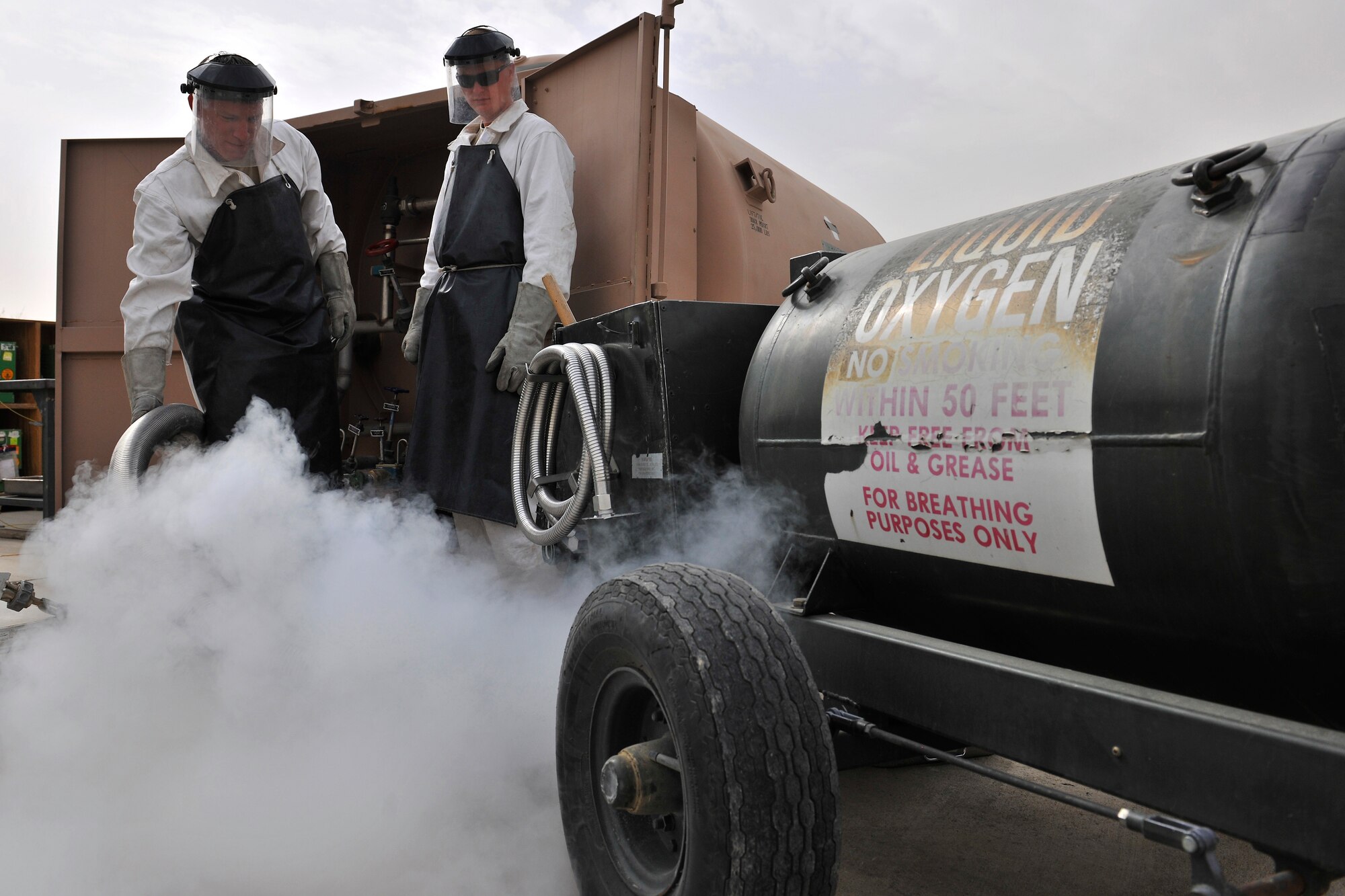 Left to right: Staff Sgt. Gregory King and Airman 1st Class Dustin Henke, assigned to the Petroleum Oils and Lubricants flight, 455th Expeditionary Logistics Readiness Squadron, fill a 50-gallon tank with liquid oxygen  at Bagram Air Field, Afghanistan, Oct. 14, 2010. LOX, stored at -297 degrees Fahrenheit, is used in aircraft for aviators to breathe and has recently been used in helicopters to supply casualties with oxygen while being transported. The fuels service center receives more than 300 fuel requests a day and are met in less than 30 minutes on average. The Petroleum Oils and Lubricants flight, ranked fourth in the Air Force for most gallons pumped, pumps 8 to 9 million gallons monthly worth about $16 million. Sergeant King is a native of Lanham, Md., and Airman Henke is a native of Waverly, Minn. (U.S. Air Force photo/Staff Sgt. Christopher Boitz)
