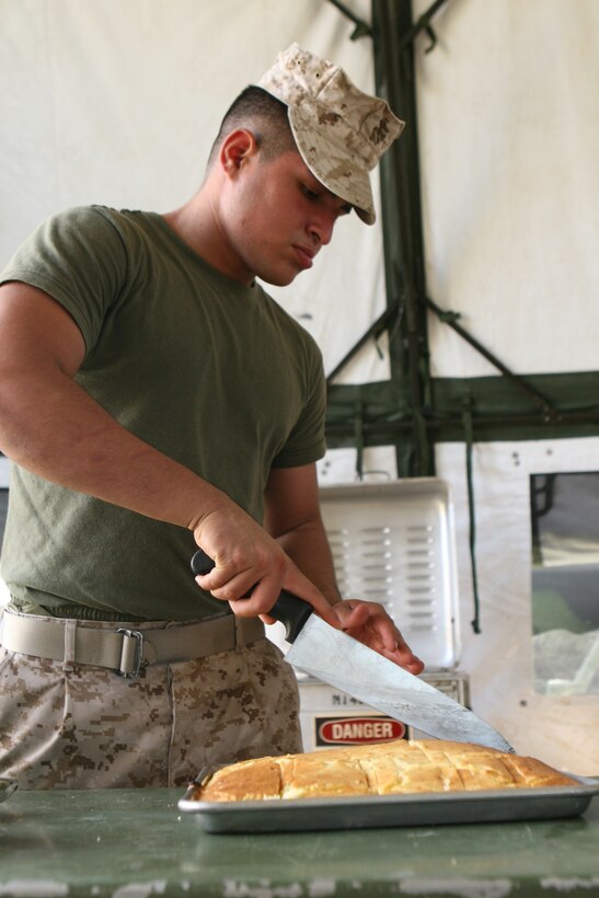 Pfc. Irving Moreno, a food service specialist with Headquarters Battery, 14th Marine Regiment, portions a tray of cornbread during evaluation and inspection for the W.P.T. Hill Award for best reserve field mess. A team of three Marine evaluators and one civilian, who are all cooks by trade, evaluated Marines on a wide range of categories from the taste of the food to the appearance and attitude of the Marines preparing the meal.