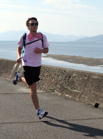 Wearing a stylish oversized, sequined pink bow, Tylor Apple runs toward the finish line at the end of the 5K walk/run to show his support for Breast Cancer Awareness Month on the seawall behind IronWorks Gym here Saturday. Apple joined his mother who brought her own flair by sporting a glamorous pink boa.