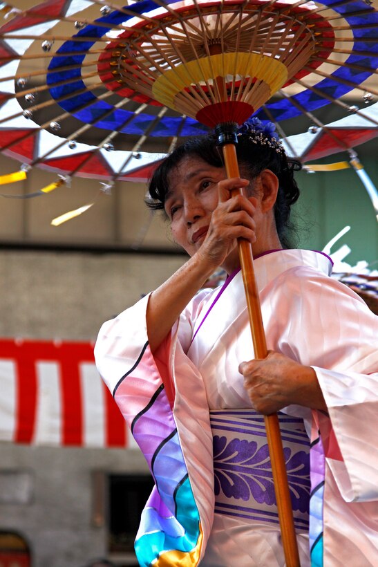A festival performer dances down the street with a decorative umbrella during the closing parade of the 54th annual Iwakuni Festival hosted in the downtown area by the train station Sunday. Various clubs from around the station also participated in the closing parade dressed in traditional yukatas or decorative costumes.