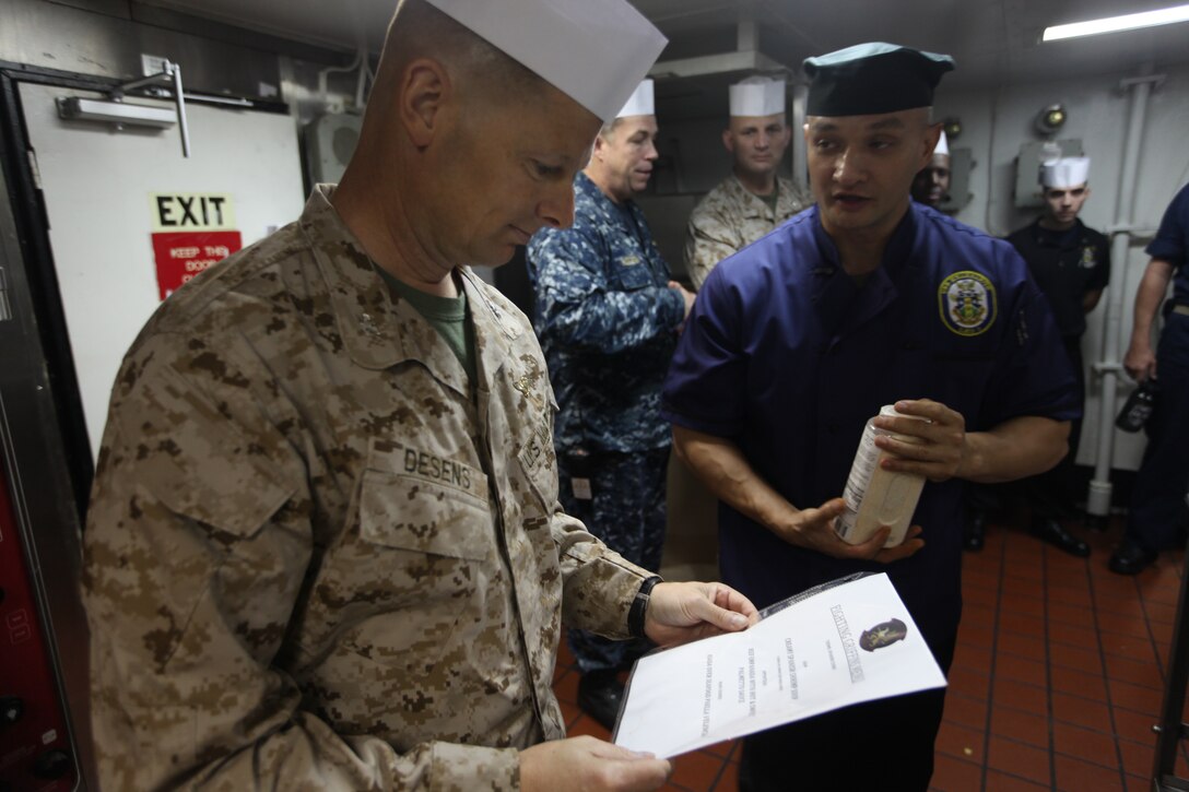 Colonel Mark Desens, commanding officer of 26th Marine Expeditionary Unit, asks questions about the planned menu to Staff Sgt. Phillip Creasor, a helicopter crew chief with Marine Medium Tiltrotor Squadron 266 (Reinforced), 26th MEU, during a Steel Chef competition aboard USS Kearsarge, Oct. 17, 2010. 26th MEU is currently embarked aboard the ships of Kearsarge Amphibious Ready Group and conducting training in the 5th Fleet area of responsibility.