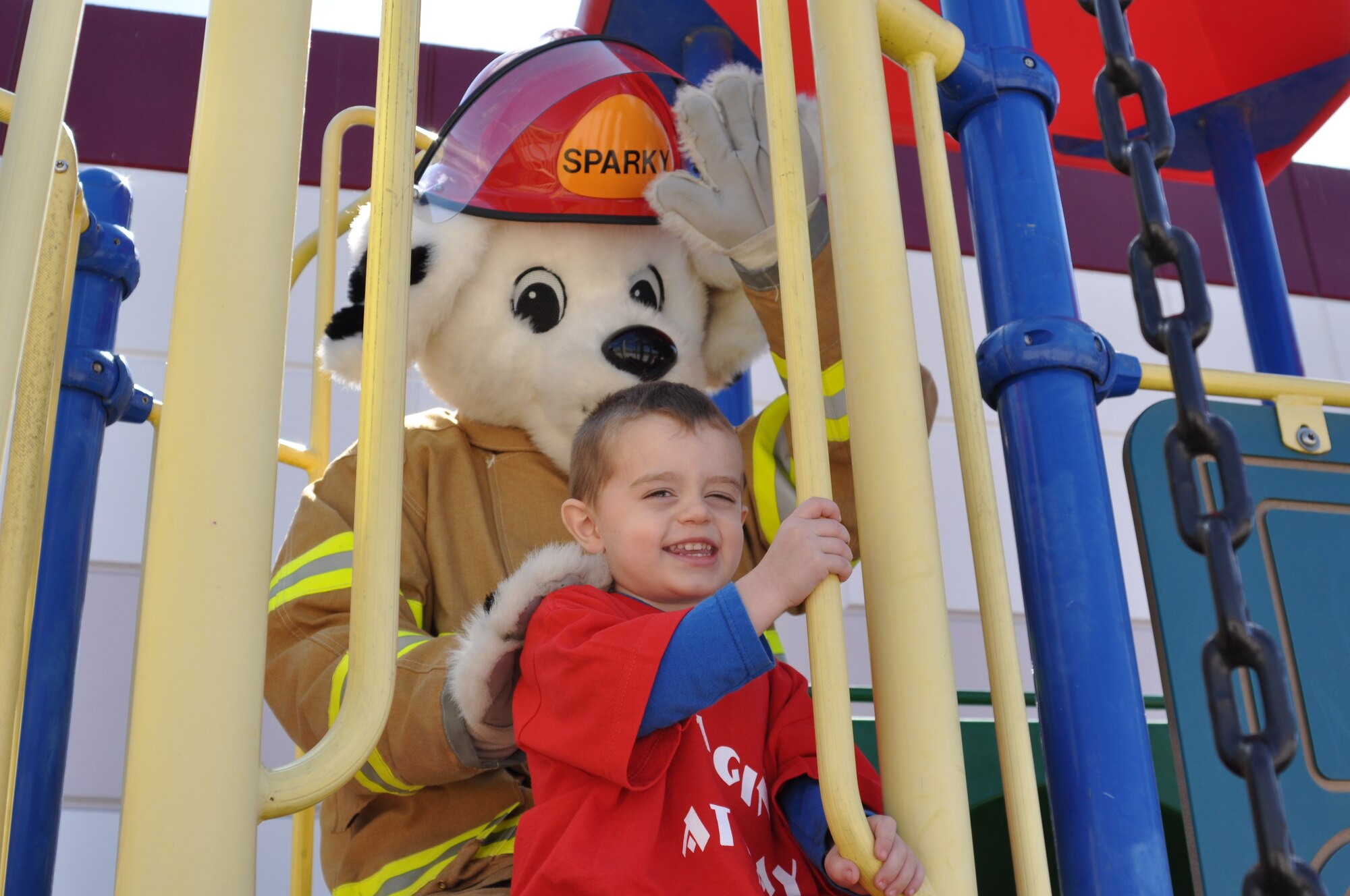 Sparky climbs on a play structure with a young boy at Emagine U at Play day care, which is located just outside March Air Reserve Base’s main gate, Oct. 7. The Fire Department wanted to expose young children to the concepts of safety at home and at play.  (U.S. Air Force photo by Linda Welz)