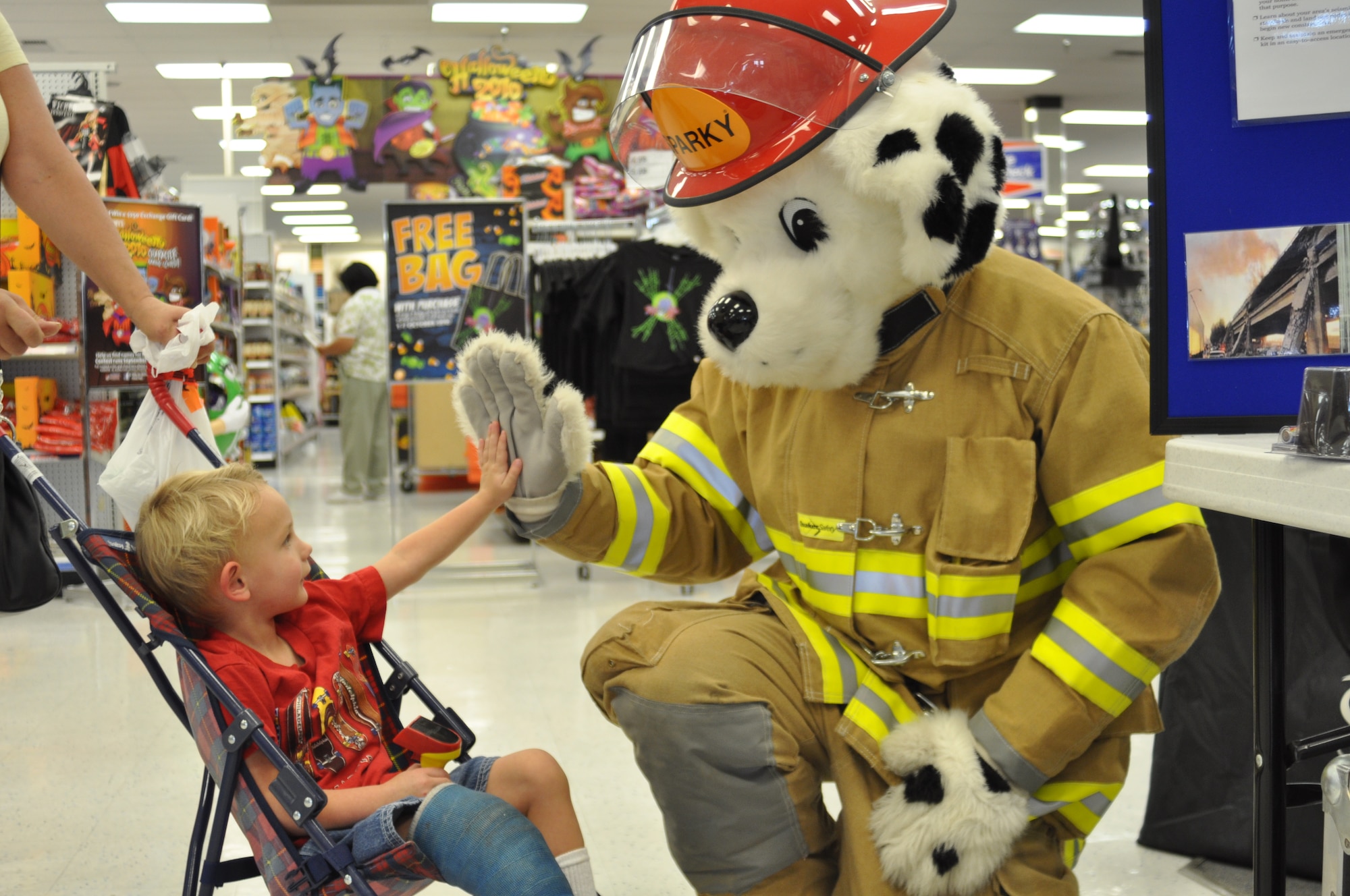 Sparky (played by March firefighter Phillip Quinn) Sparky gives a high five to Broc Johnson, 3, a military grandson who was shopping with his grandmother Oct. 7. (U.S. Air Force photo by Linda Welz)