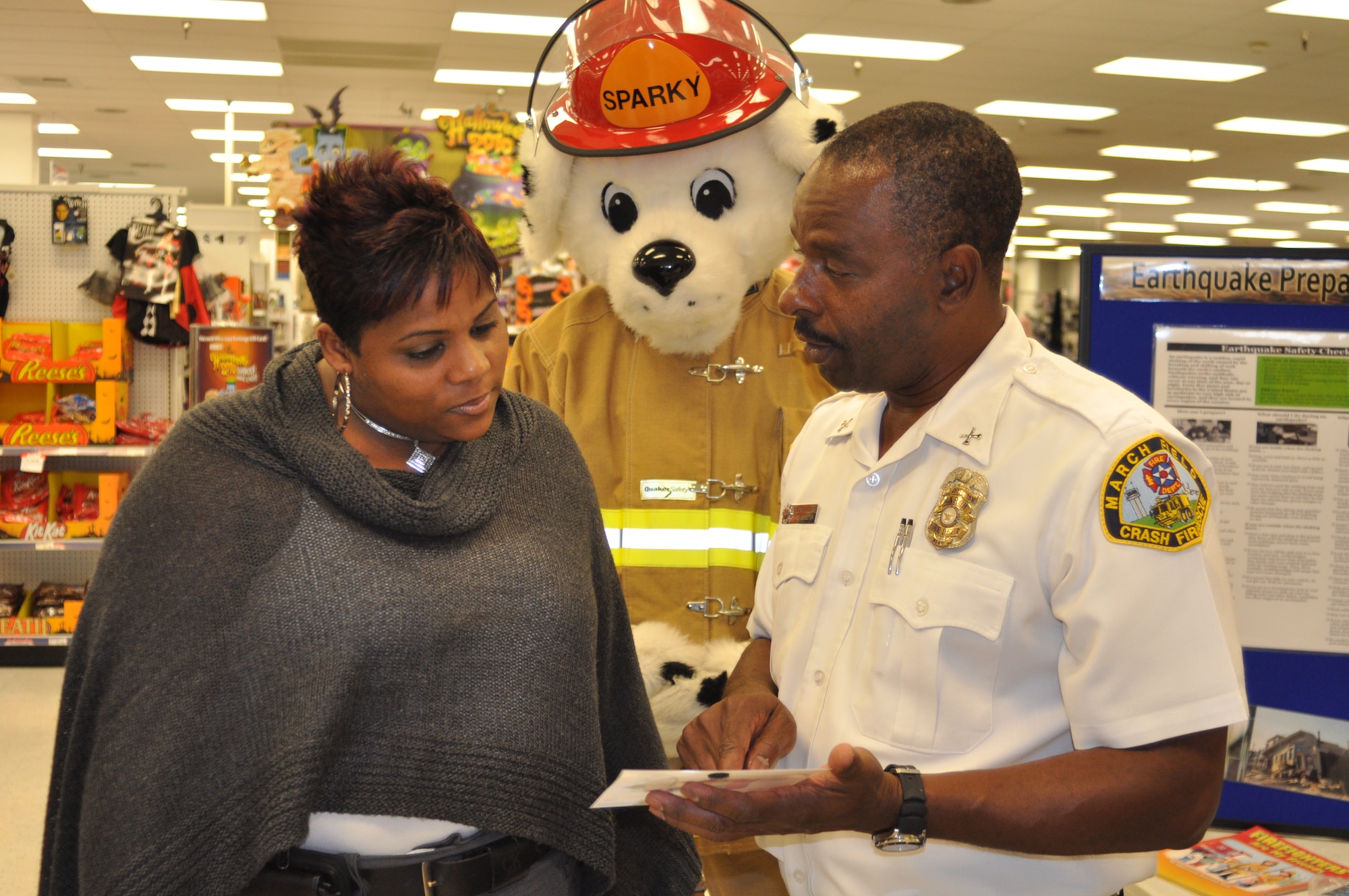 Sparky (played by March firefighter Phillip Quinn) and Inspector Timothy Williams speak with Idell Stokes, Exchange services business manager, in front of a display the Fire Department hosted at the base exchange Oct. 7.  (U.S. Air Force photo by Linda Welz)