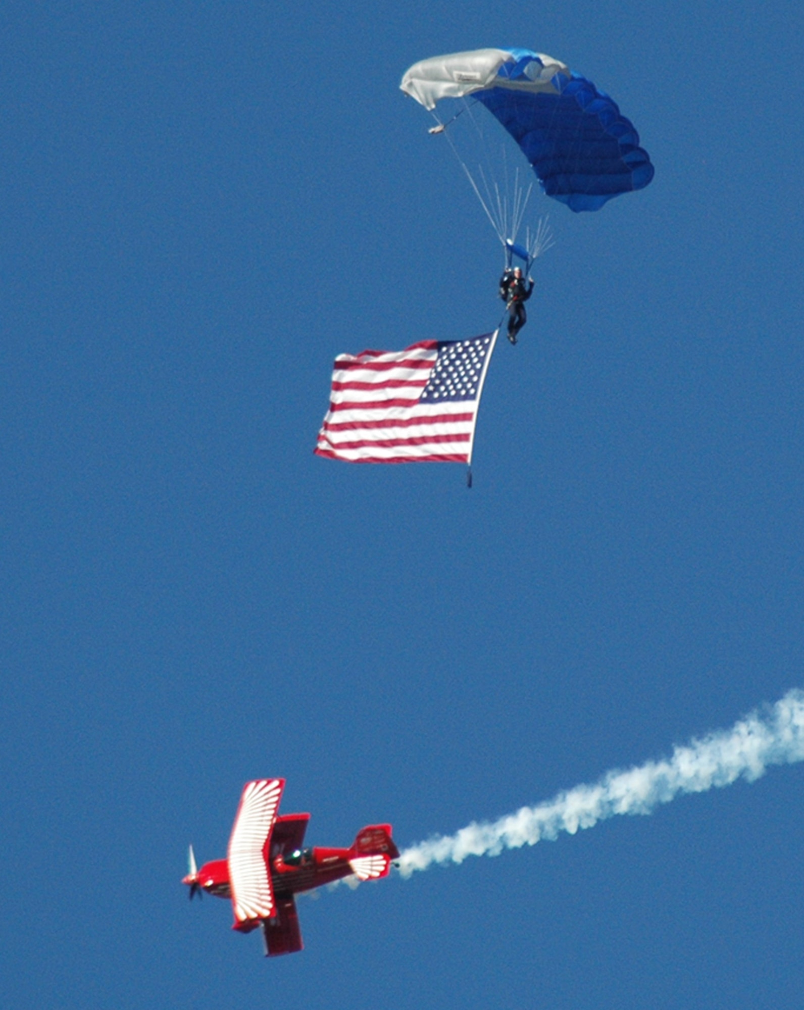 A Red Eagle bi-plane performs a perfect manuever beneath a member of the Wings of Blue Air Force Parachute Demonstration Team.  The team performed during the opening ceremony of the Wings Over Atlanta 2010 Air Show Oct.16.  (U.S. Air Force photos/Master Sgt. Dennis Travon)
