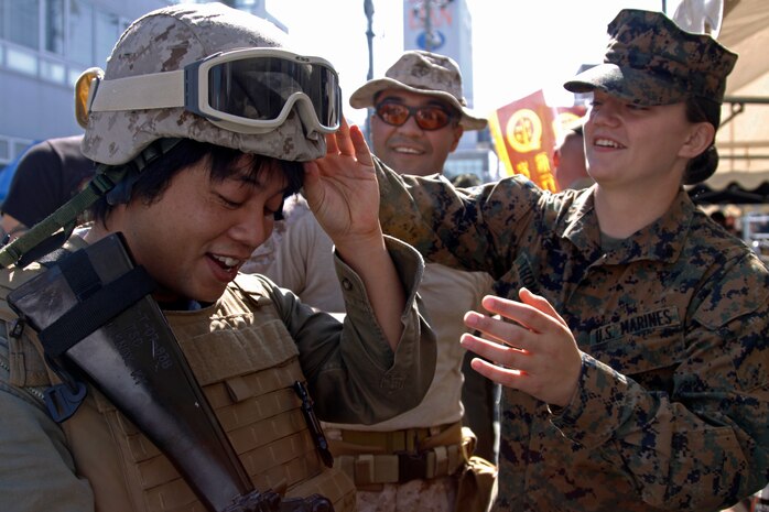 Lance Cpl. Elizabeth Thompson, a Combat Logistics Company 36 maintenance management specialist, puts a kevlar helmet on a local attending the 54th annual Iwakuni Festival hosted in the downtown area by the train station Sunday. More than 20 Marines with Marine Wing Support Squadron 171 and CLC-36 went to the festival dressed in their favorite uniforms to meet and greet locals. Approximately 98,000 people attended the festival hosted by the city of Iwakuni, Iwakuni Chamber of Commerce and Industry and the Iwakuni Tourism Association.