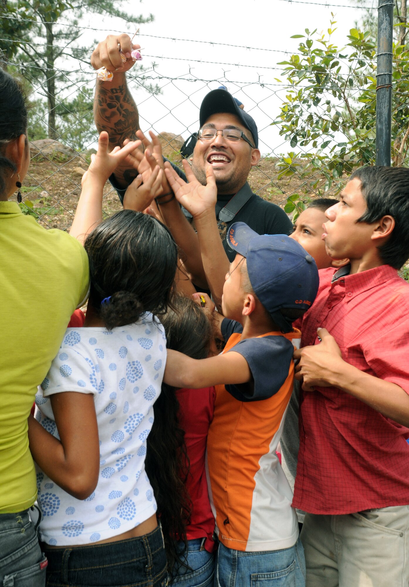 SAN JERONIMO, Honduras --  Surrounded by the village children here, Senior Airman Michael Reyes, of the Army Forces at Soto Cano Air Base, hands out candy during a Chapel Hike here Oct. 16. With the help of local leaders, the Joint Task Force-Bravo Chapel conducts regular hikes to remote towns and villages near Soto Cano to deliver food and other supplies to those in need. (U.S. Air Force photo/Tech. Sgt. Benjamin Rojek)