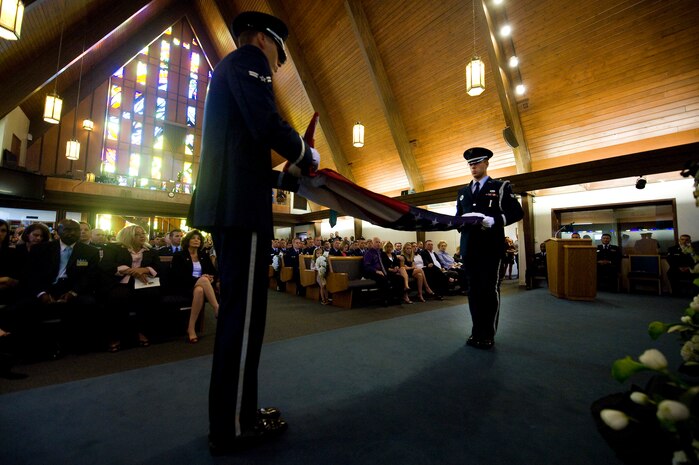 NELLIS AIR FORCE BASE, Nev. -- Nellis Honor Guard performs the flag-folding ceremony inside the base chapel during the memorial service of Senior Airman Michael Buras Oct. 15. Senior Airman Buras was an Explosive Ordnance Disposal Journeyman assigned to the 99th Civil Engineer Squadron. Airman Buras was killed in action while deployed to Afghanistan and responding to an Improvised Explosive Device Sept. 21.  (U.S. Air Force photo by Senior Airman Brett Clashman/Released)

