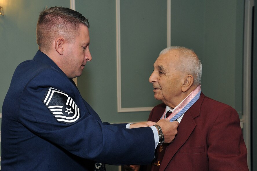 OFFUTT AIR FORCE BASE, Neb. - Senior Master Sgt. Matthew Becker, 55th Maintenance Squadron, places a medallion around the neck of Sam Sambasile, a former prisoner of war, during the 16th Annual Prisoner of War/Missing in Action remembrance ceremony held at the Patriot Club Oct. 13. As part of the ceremony, a POW/MIA table is set by the Offutt Honor Guard with specific symbolic items in rememberance and to honor all American former prisoners of war, servicemembers and civilians still unaccounted for, and their families. These items include a slice of lemon to represent the bitter fate of prisoners of war or those missing in action, a pinch of salt to represent the tears shed by the one missing or captured and their family, and an inverted glass showing the inability of those listed as POW/MIA to share in the toast for the evening. U.S. Air Force photo by Charles Haymond 
