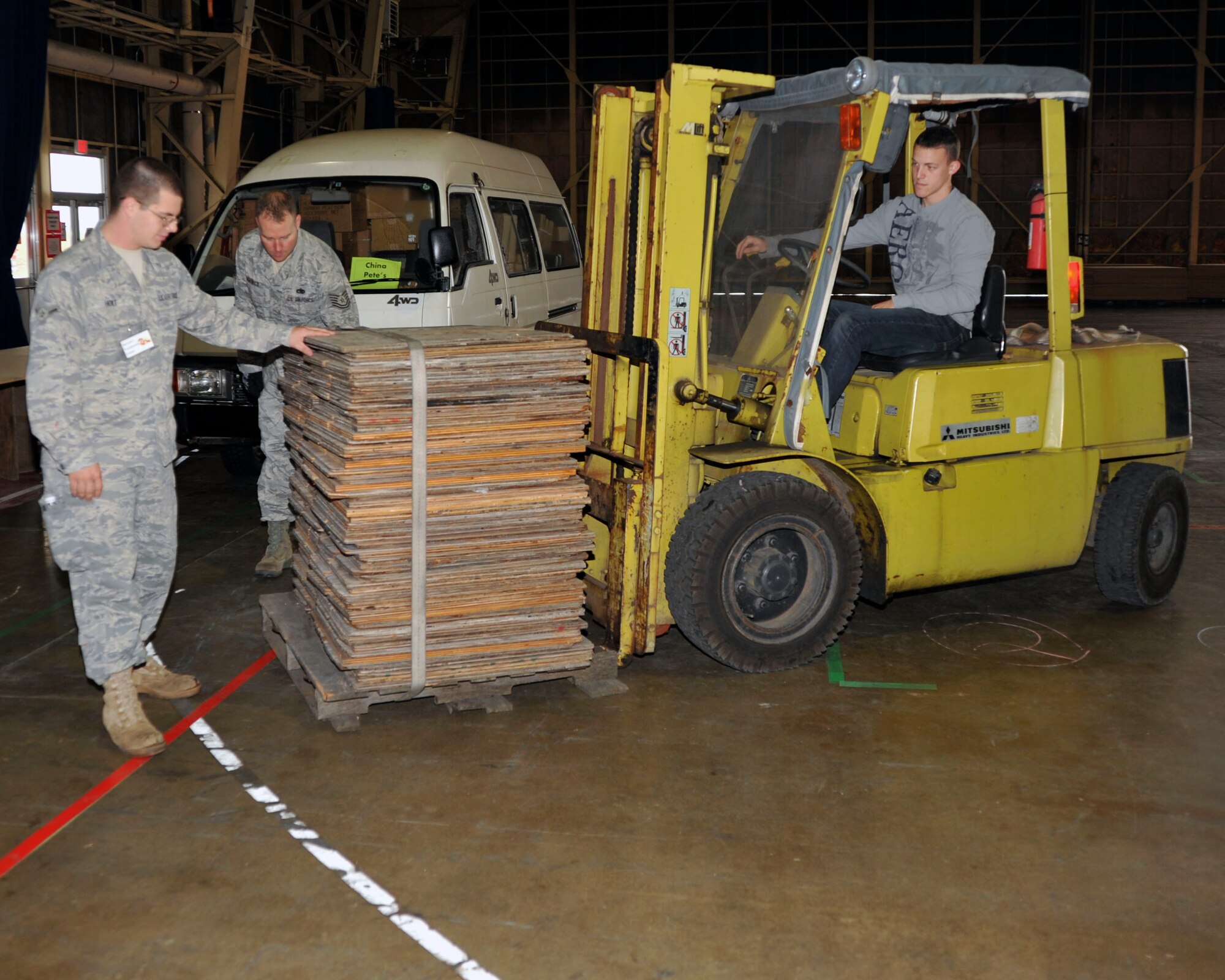 U.S. Air Force Airman 1st Class Christopher Backers, right, 35th Maintenance Squadron propulsion flight, uses a fork lift to move wooden braces during the set up of the Far East Bazaar at Misawa Air Base, Japan, Oct. 15, 2010. Airman Corey Holt, 35 MXS/MXMCG, guides Airman Backers as he lowers table brackets for vendor's tables, more than 125 were tables were assembled. (U.S. Air Force photo by Tech. Sgt. Russell McBride/Released) 