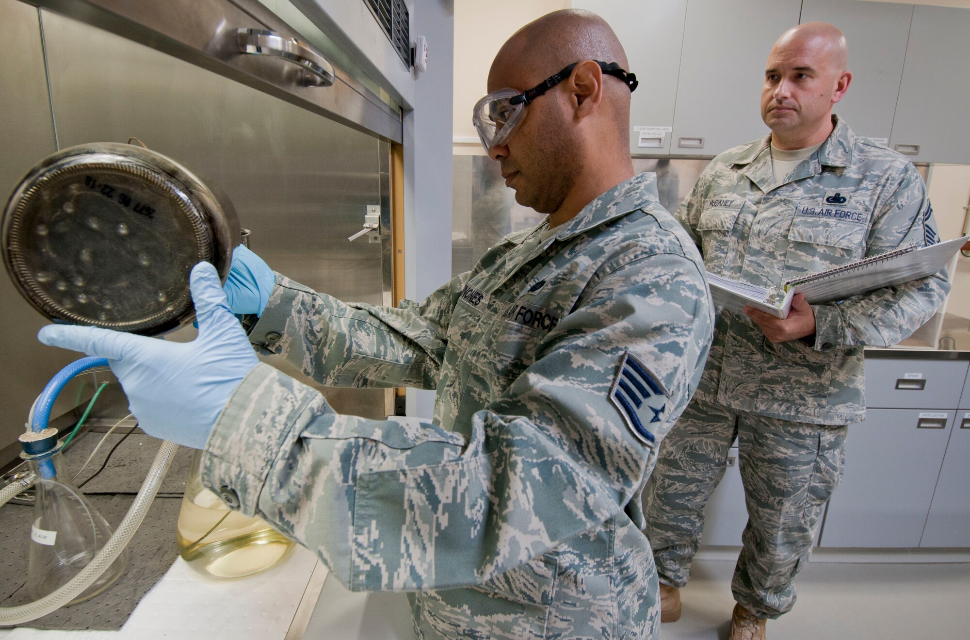 Staff Sgt Antonio Quinones, 35th Logistics Readiness Squadron Petroleum Oils and Lubricants laboratory supervisor, pours fuel through a filter as Senior Master Sgt. Eric McGahey, a Logistics Compliance Assessment Program team POL inspector, monitors his progress, Oct. 18, 2010, at Misawa Air Base, Japan. LCAP inspectors from Air Combat and Pacific Air Forces Commands are assessing 35th Fighter Wing logistics and maintenance functions and procedures Oct. 18 to 22, scrutinizing for safety, compliance and proficiency. (U.S. Air Force photo/Senior Airman Jessica Lockoski/Released)