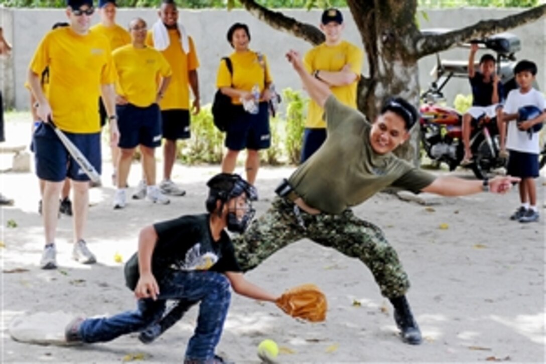 Philippine Navy Ensign Crispin Cristal tries to beat a throw home during a pickup softball game as part of a community outreach event at San Esteban Elementary School in San Antonio, Philippines, Oct. 14, 2010. The U.S. sailors are assigned to Amphibious Squadron 11. The Philippine sailors donated educational and recreational materials to the school. 