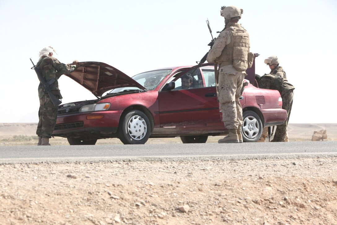 Marines and Afghan National Army soldiers search a car passing through on Route 606 in Demazong, Afghanistan, Oct. 18. Marines and Afghan soldiers checked vehicles passing by for contraband including improvised explosive devices and materials used to make IEDs, the Taliban’s weapon of choice against coalition forces.