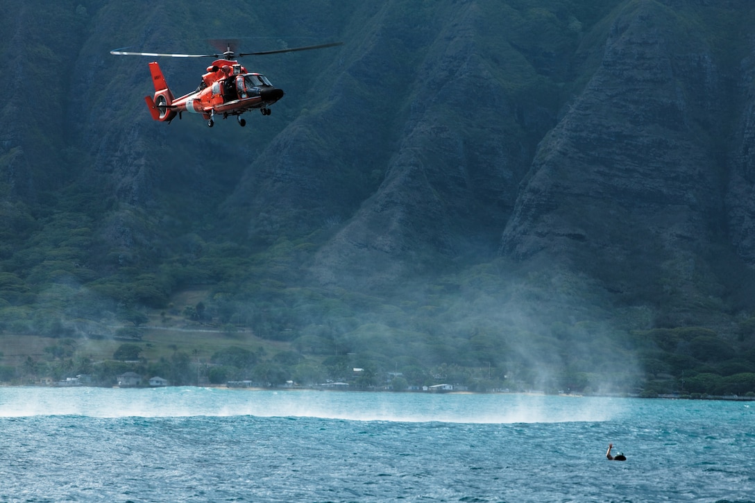 A Coast Guard Eurocopter HH-65 Dolphin helicopter moves toward simulated casualty Cpl. Brad Rosati, a navigation aids technician with Air Traffic Control maintenance, Marine Corps Air Station Kaneohe Bay, during a joint-service aircraft mishap drill over Kaneohe Bay, Hawaii, Oct. 18, 2010. Built on the premise of a simulated CH-53D Sea Stallion helicopter crash over water, the drill allowed the joint-service team to work through standard operating procedures for air and waterborne rescue operations.