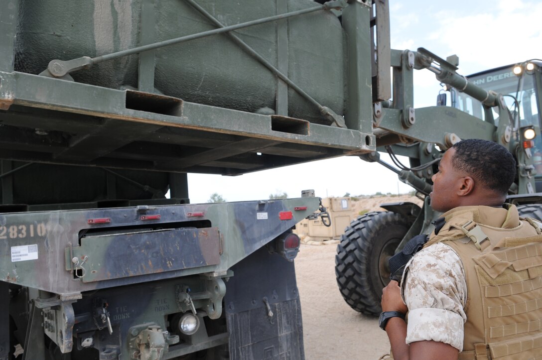 Lance Cpl. Dominic Dsouza, Combat Logistics Company 16 motor transportation mechanic, directs an operator while he loads a 7-ton truck with an empty water container at a training site near the Chocolate Mountain Aerial Gunnery Range Oct. 18, 2010. The task was part of convoy operations by CLC-16, Combat Logistics Regiment 15 and 17, and 7th Engineering Support Battalion. They supported ground units at various Yuma training sites with food, water, fuel and maintenance personnel.