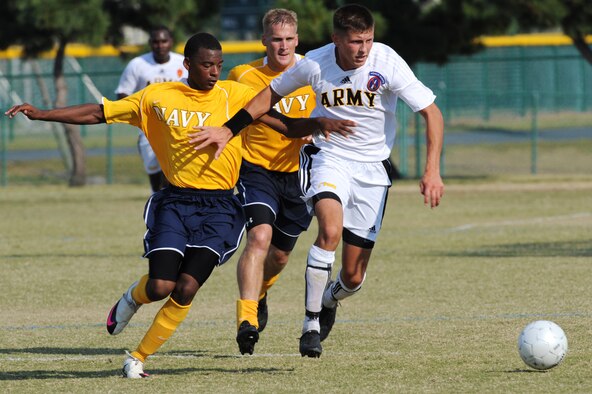 U.S. Navy Information Technichian Seaman Apprentice Kyle Baker, assigned to United States Ship Enterprise, Norfolk, Va., a forward for the USN soccer team, races U.S. Army Sgt. Tyler Stratford, assigned to Fort Myer, Va., a midfielder for the USA soccer team, for control of the ball as U.S. Navy Lt. Michael Tuddenham, assigned to Defense Distribution Depot, Susquehanna, Pa., moves to assist during an Armed Forces Men's Soccer Championship Round Robin match at Morgan Sports Complex, Destin Fla., Oct. 19, 2010.  Each team conducted highly competitive training programs and trial camps in order to select the best players to represent their respective services.  However, at the conclusion of the tournament, inter-service rivals will cast aside their differences.  The top players from the tournament will be chosen to represent the US in the International Military Sports Competition.  (DoD photo by U.S. Air Force 1st Lt. Belena S. Marquez/RELEASED)
