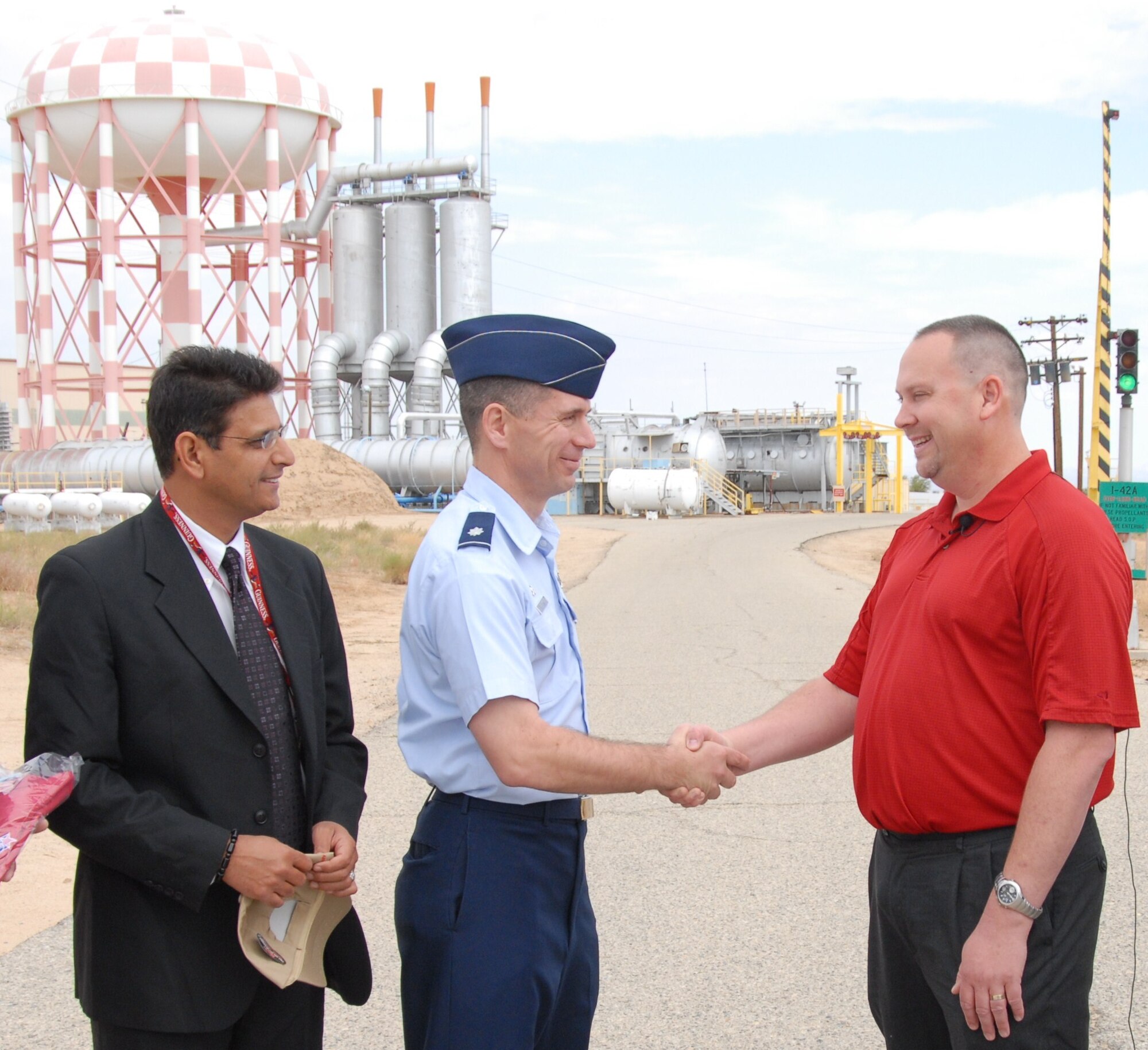 Dr. Ashwani Vij (left), AFRL Volunteer Protection Program manager, watches Lt. Col. Michael H. Platt, Air Force Research Laboratory Det. 7 commander, present Dan Harbour with a commander's coin for helping a choking coworker, Oct. 18. (Air Force photo by Kenji Thuloweit)
