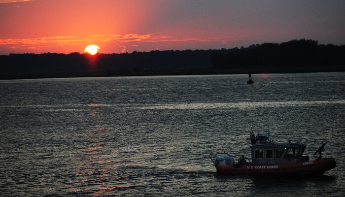 A U.S. Coast Guard boat patrols the waters during a cargo off-load at the TC dock Oct. 14, 2010, on Joint Base Charleston-Weapons Station, S.C. The USCG supports the Transportation Command by providing 24-hour protection for all vessels traveling in and out of port at the JB CHS-WS. The USCG has many missions and duties ranging from drug interdiction, search and rescue, migrant interdiction and other law encorcement duties.(U.S. Air Force photo/Senior Airman Timothy Taylor)