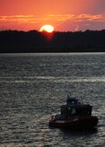 A U.S. Coast Guard boat patrols the waters during a cargo off-load at the TC dock Oct. 14, 2010, on Joint Base Charleston-Weapons Station, S.C. The USCG supports the Transportation Command by providing 24-hour protection for all vessels traveling in and out of port at the JB CHS-WS. The USCG has many missions and duties ranging from drug interdiction, search and rescue, migrant interdiction and other law encorcement duties.(U.S. Air Force photo/Senior Airman Timothy Taylor)