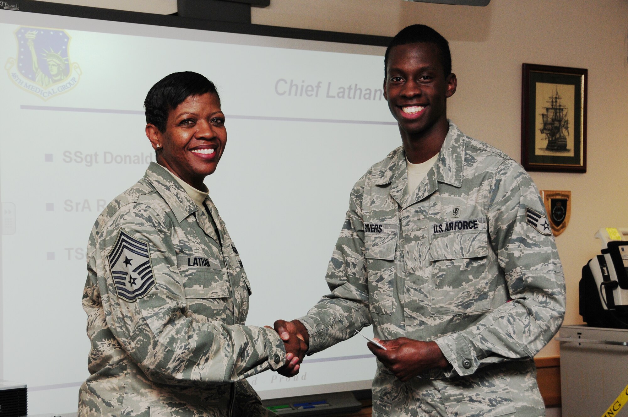 ROYAL AIR FORCE LAKENHEATH, England – Chief Master Sergeant SaRita Lathan, 48th Fighter Wing command chief, presents Staff Sergeant Donald Byrd, 48th Medical Support Squadron medical readiness journeyman, with a coin on behalf of Retired Chief Master Sgt. Pamela Derrow, former United States Air Forces in Europe command chief Oct. 15. Airman Rivers and five other Liberty Wing Airmen were recognized for their outstanding performance and exemplifying Integrity First, Service Before Self and Excellence In All We Do. (U.S. Air Force photo/Airman 1st Class Lausanne Morgan)