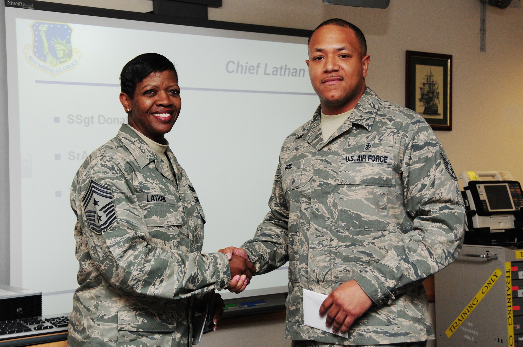 ROYAL AIR FORCE LAKENHEATH, England – Chief Master Sergeant SaRita Lathan, 48th Fighter Wing command chief, presents Staff Sergeant Donald Byrd, 48th Medical Support Squadron productions NCO in-charge, with a coin on behalf of Retired Chief Master Sgt. Pamela Derrow, former United States Air Forces in Europe command chief Oct. 15. Sergeant Byrd and five other Liberty Wing Airmen were recognized for their outstanding performance and exemplifying Integrity First, Service Before Self and Excellence In All We Do.(U.S. Air Force photo/Airman 1st Class Lausanne Morgan)