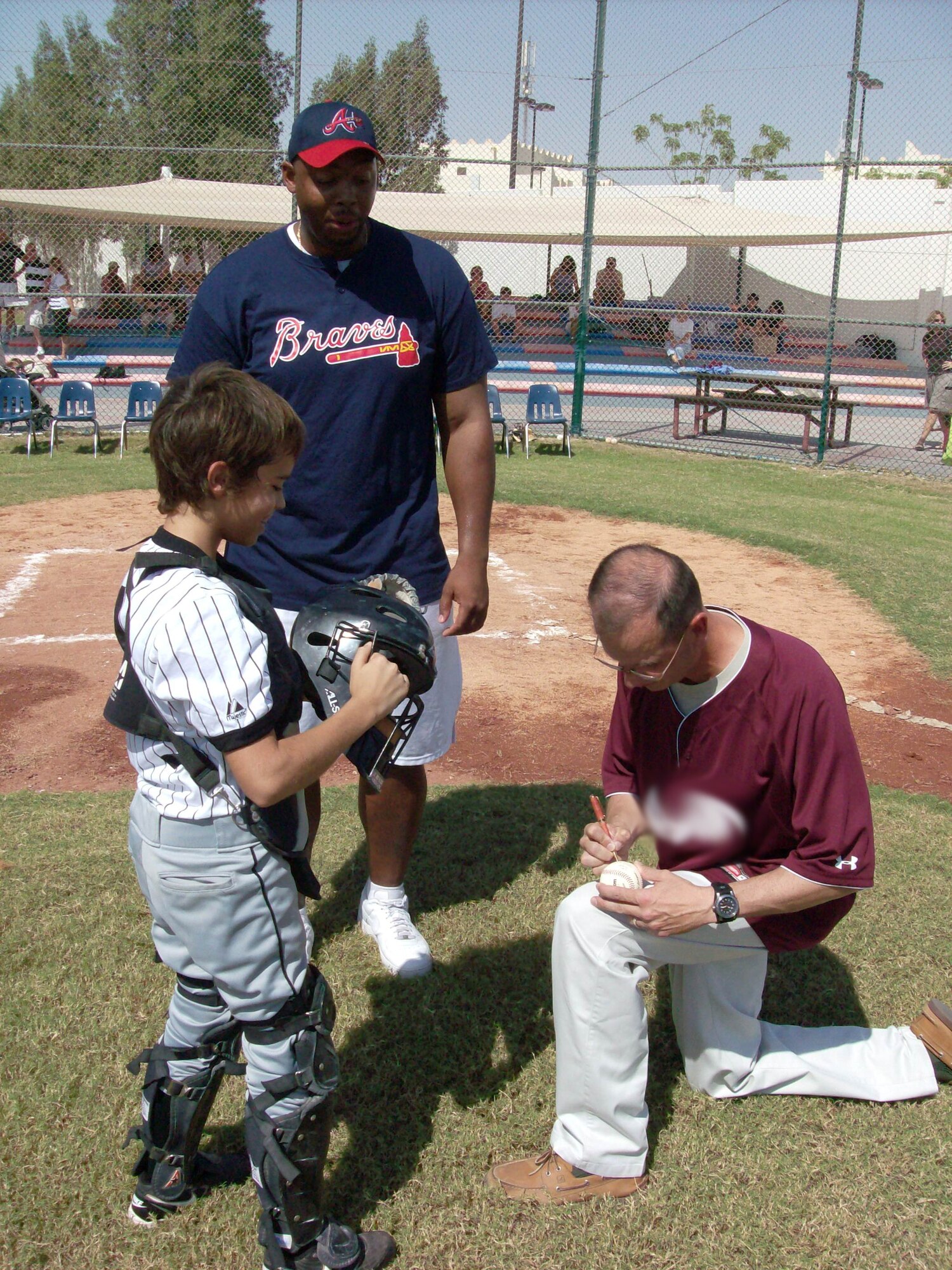 SOUTHWEST ASIA - Brig. Gen. Randy Kee, commander of the 379th Air Expeditionary Wing,autographs a baseball after throwing out the ceremonial first pitch at the little league annual season opener here, Oct. 15, marking the league?s 13th season.   Kids from more than 20 different nationalities play American baseball at our host nation's American High School. (U.S. Air Force photo/Maj. James Peterson)