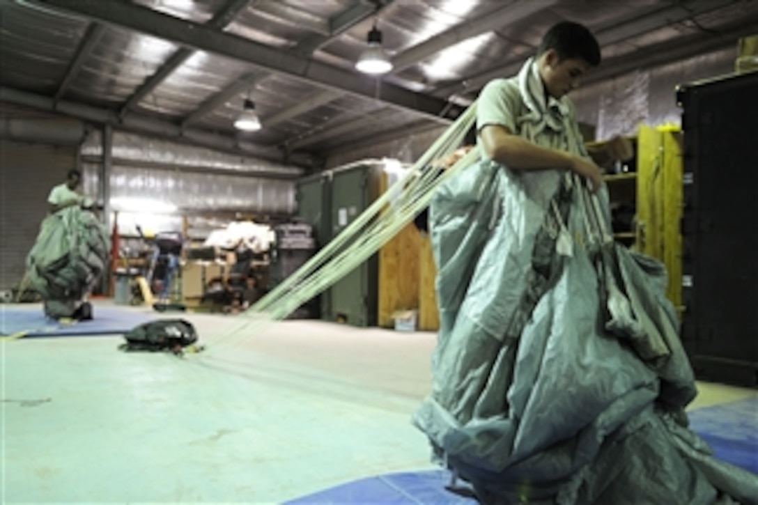 U.S. Air Force Airman 1st Class Roger Walters (right) and Senior Airman James Perry pack parachutes at Camp Lemonier, Djibouti, on Oct. 12, 2010.  Walters and Perry are both aircrew flight equipment journeymen with the 82nd Expeditionary Rescue Squadron and support pararescuemen by maintaining and issuing flight equipment, night-vision goggles, oxygen systems and parachutes.  The squadron is deployed in support of Combined Joint Task Force - Horn of Africa.  