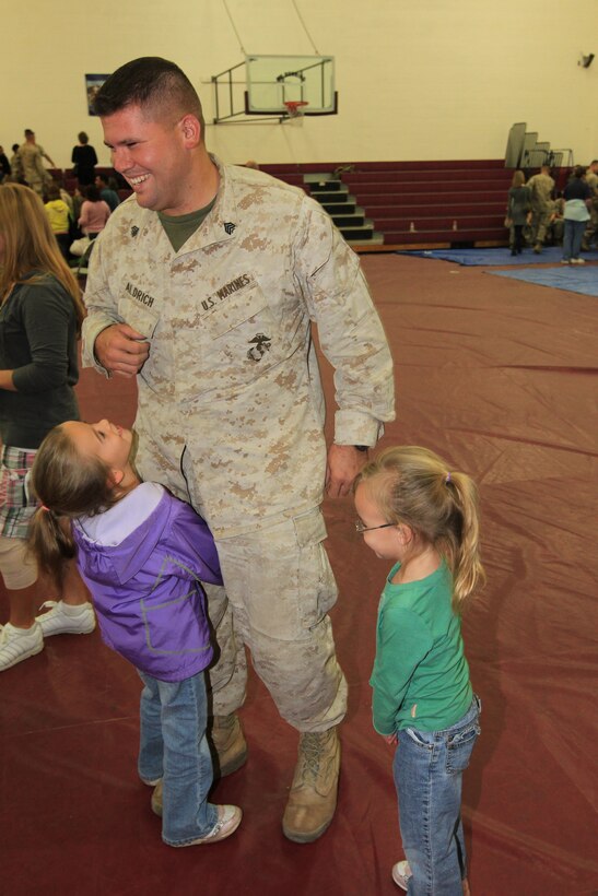 Sergeant Jeremy Aldrich, a communications maintenance technician with Company L, 3rd Battalion, 7th Marine Regiment, gets a warm welcome from his family friend’s children, Elizabeth, 6, [Left], and Alexis, 3, [Right] during Company L’s homecoming at the Combat Center’s West Gym Oct. 20, 2010.::r::::n::