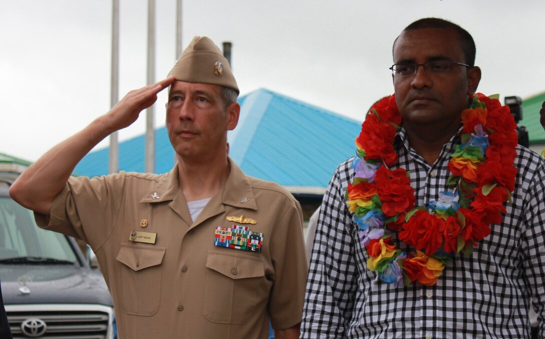 Navy Capt. Thomas M. Negus, commodore of Continuing Promise 2010, stands with Guyana President H.E. Bharrat Jagdeo and salutes the U.S. flag while the American National Anthem plays during the CP10 opening ceremony held at the Berbice Regional Health Authority, Oct. 20, 2010.