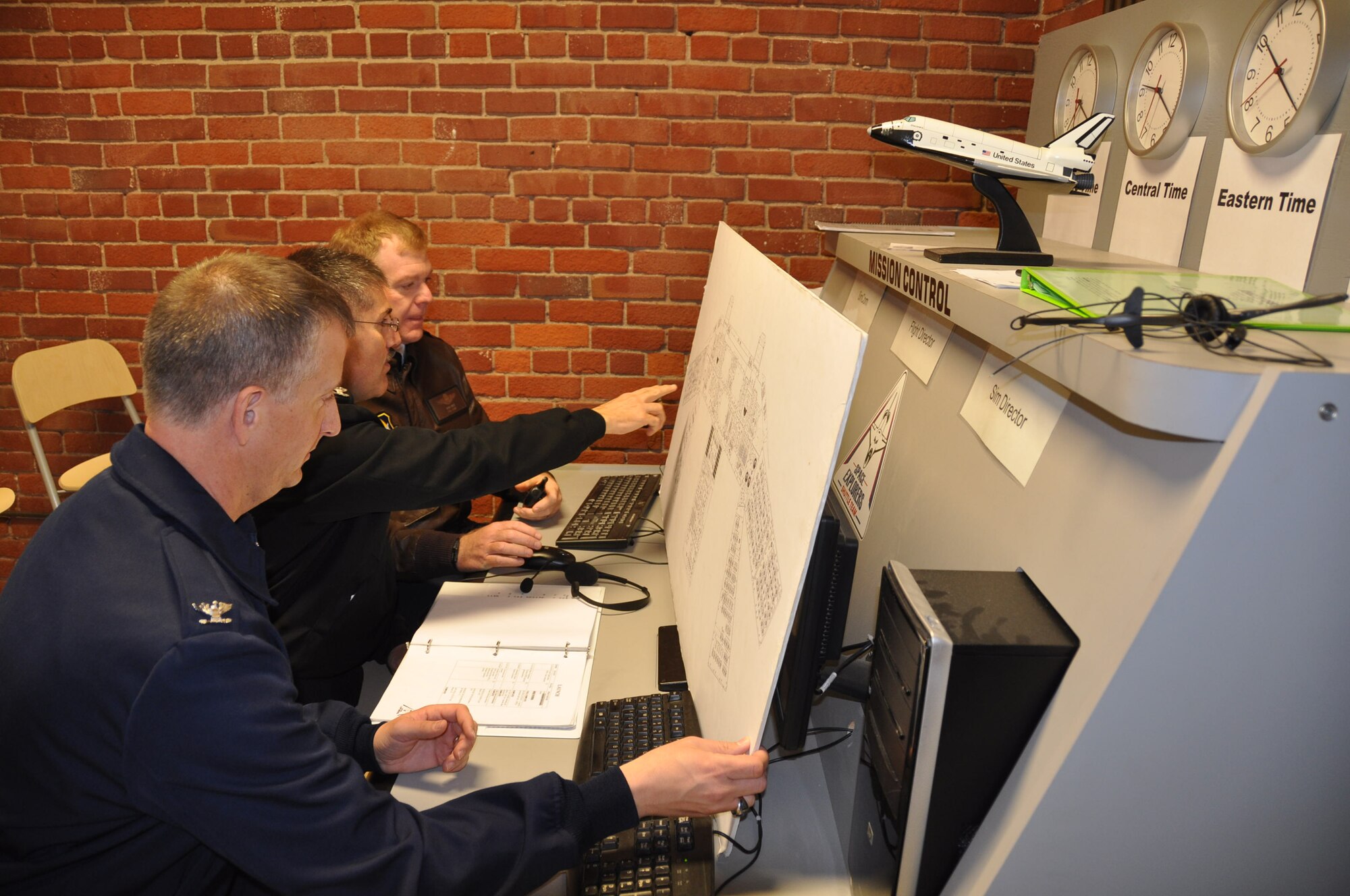 Col. Brett Newman, Capt. Kevin Hempel and Col. Ron Wilt sit at the helm of Mission Control at the Base Camp Space Shuttle simulator. (Air Force Photo/Paul Zadach)