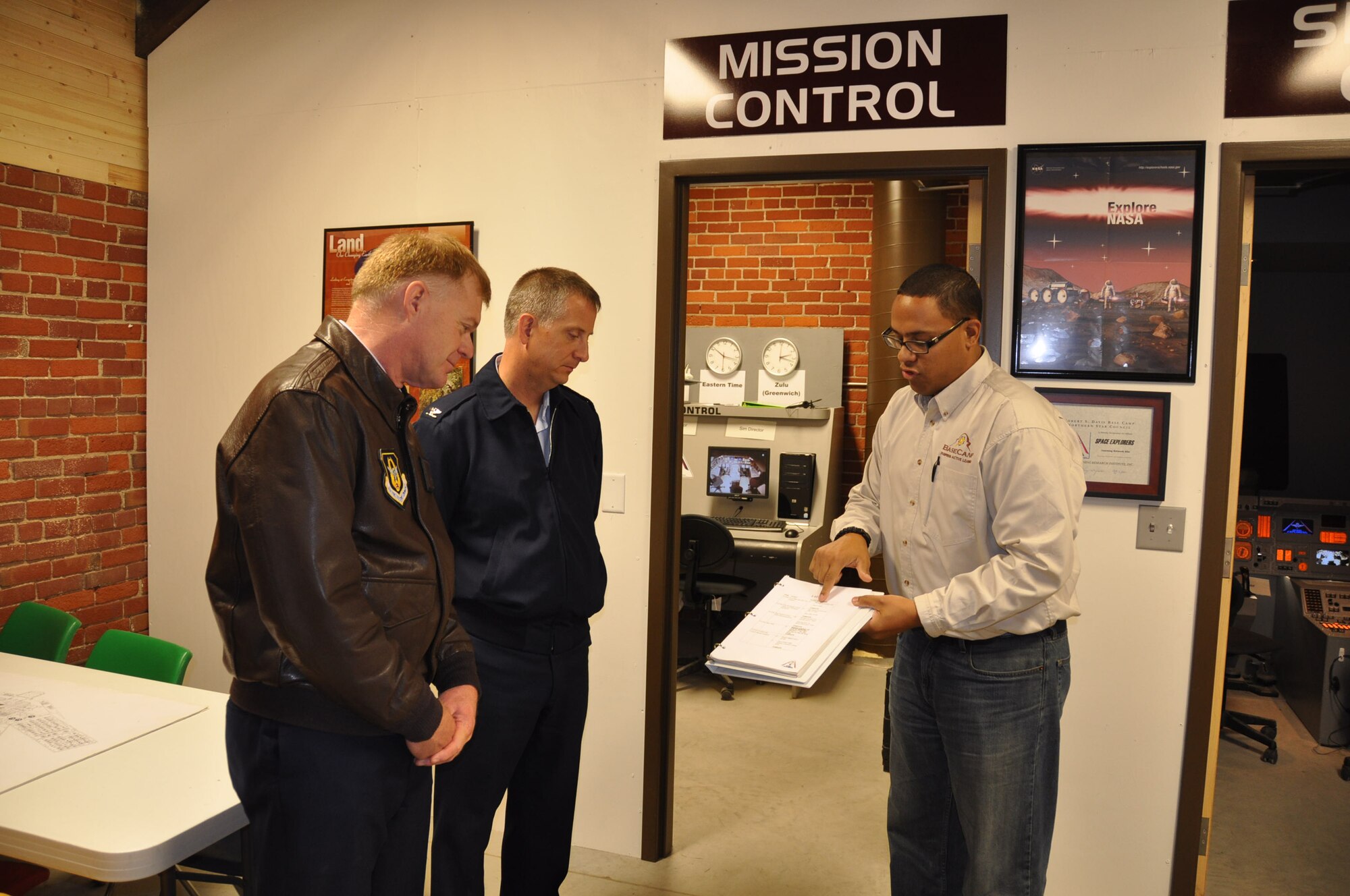 Col. Ron Wilt (left) and Col. Brett Newman get instructions on piloting the Space Shuttle simulator from Jonathan Jones at the Boy Scout Base Camp.(Air Force Photo/Paul Zadach)