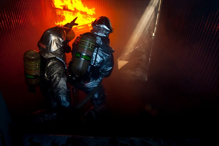 NELLIS AIR FORCE BASE, Nev. -- Staff Sgt. Aric Andrade, 99th Civil Engineer Squadron fire department crew chief, directs Brig. Gen. David Thompson, U.S Air Force Warfare Center vice commander, on the proper technique to attack a structural fire at the Nellis live fire training facility Oct. 18. The 99th Civil Engineer Squadron and Fire Emergency Services Flight invited the Wing leadership to a live-fire aircraft and structural exercise so they could get to experience some of the challenges firefighters encounter during real world situations. (U.S. Air Force photo by Tech. Sgt. Michael R. Holzworth)(Released)