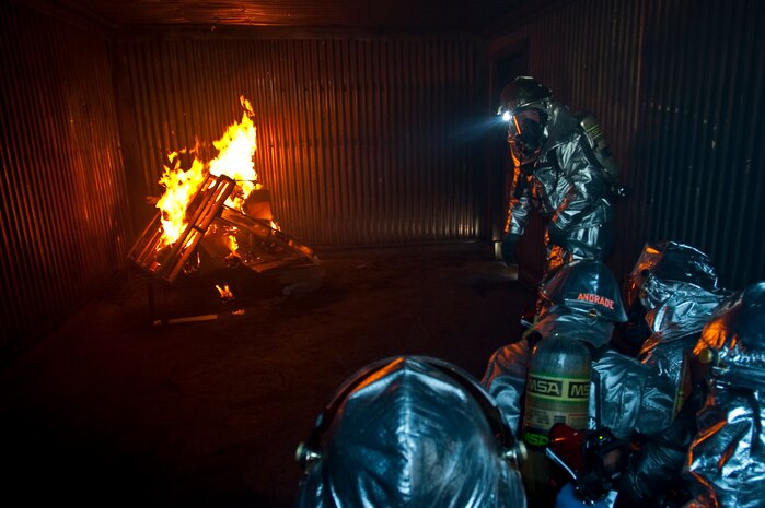 NELLIS AIR FORCE BASE, Nev. -- Staff Sgt. Matthew Supnick a crew chief with the 99th Civil Engineer Squadron Fire Department makes sure the room is safe during structural fire training with Col. Steven Garland, 99th Air Base Wing commander and Brig. Gen. David Thompson, U.S Air Force Warfare Center vice commander at the Nellis live-fire training facility Oct. 18. The 99th Civil Engineer Squadron and fire emergency services flight invited Nellis senior leaders to a live-fire aircraft and structural exercise so they could experience some of the challenges firefighters encounter during real-world situations. (U.S. Air Force photo by Tech. Sgt. Michael R. Holzworth)(Released)